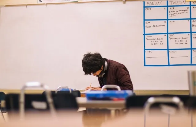 A student alone in a classroom doing work.